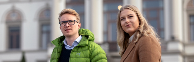 En kvinne og en mann står foran en bygning